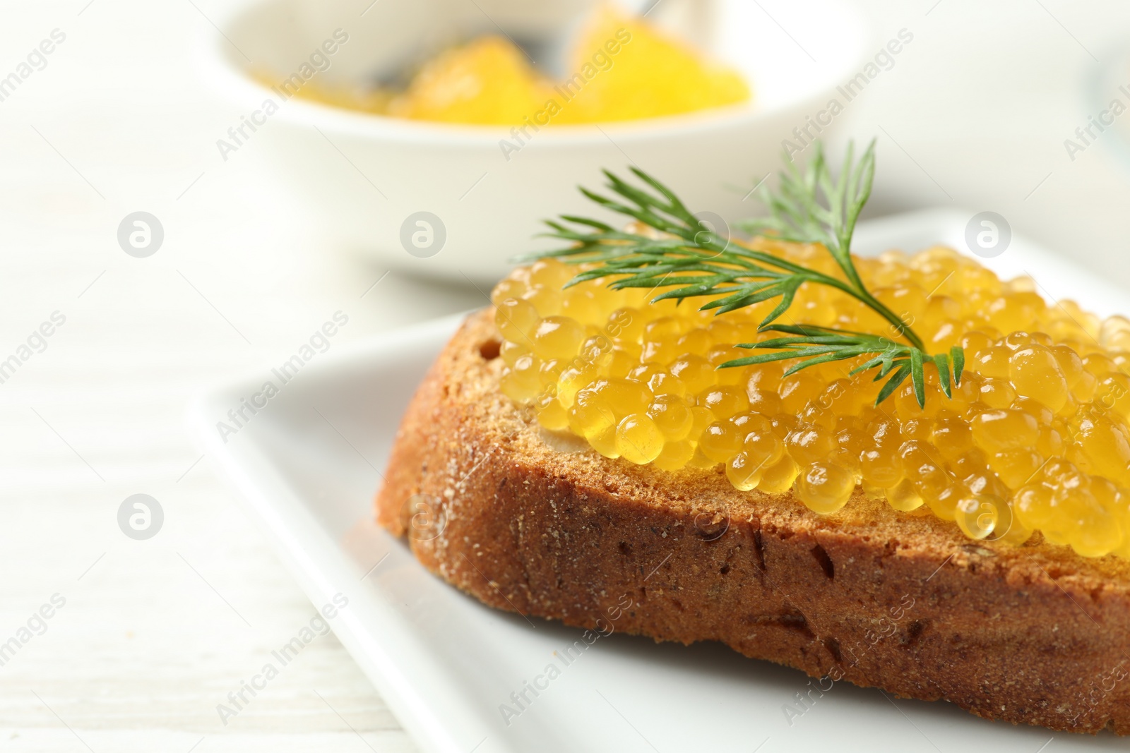 Photo of Slice of bread with pike caviar on white wooden table, closeup