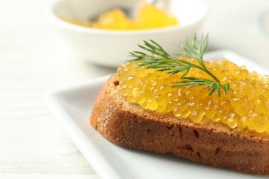 Slice of bread with pike caviar on white wooden table, closeup