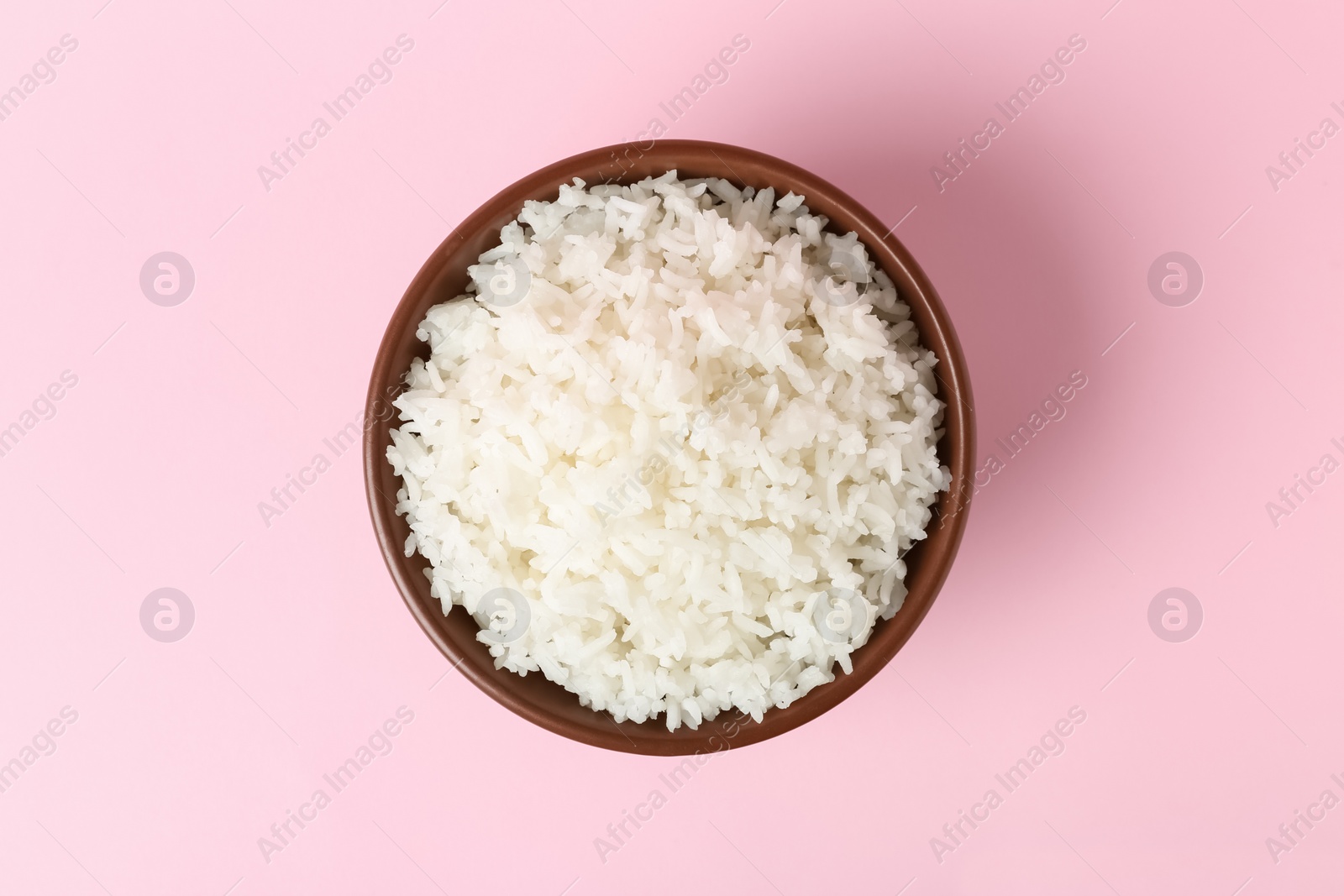 Photo of Bowl of boiled rice on color background, top view