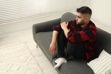 Photo of Sad lonely man on sofa at home. Space for text