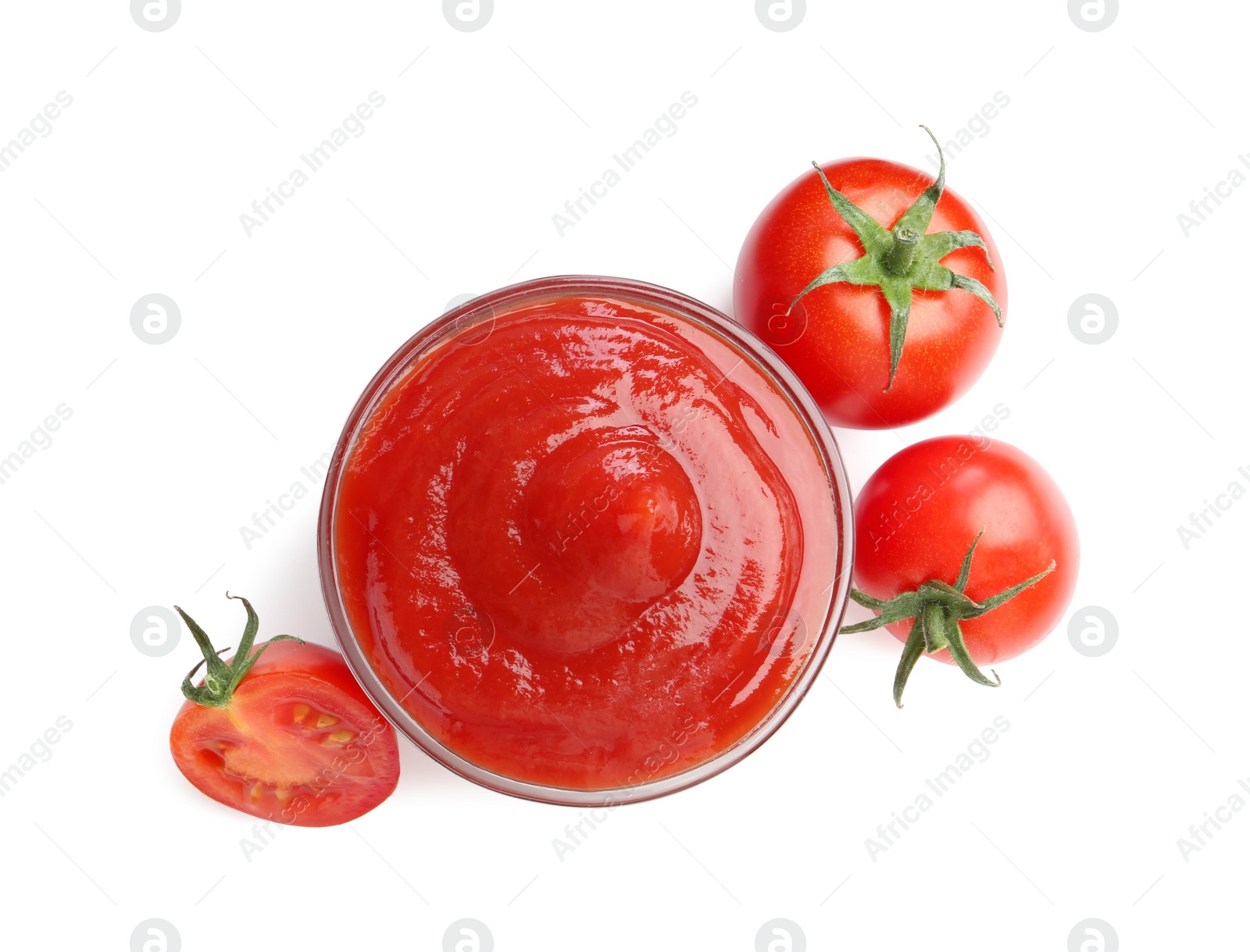 Photo of Tasty ketchup in glass bowl and fresh tomatoes isolated on white, top view