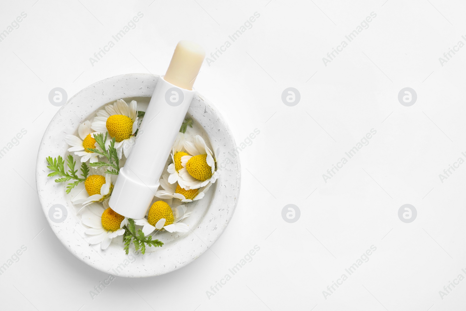Photo of Hygienic lipstick, chamomile flowers and marble tray on white background, top view