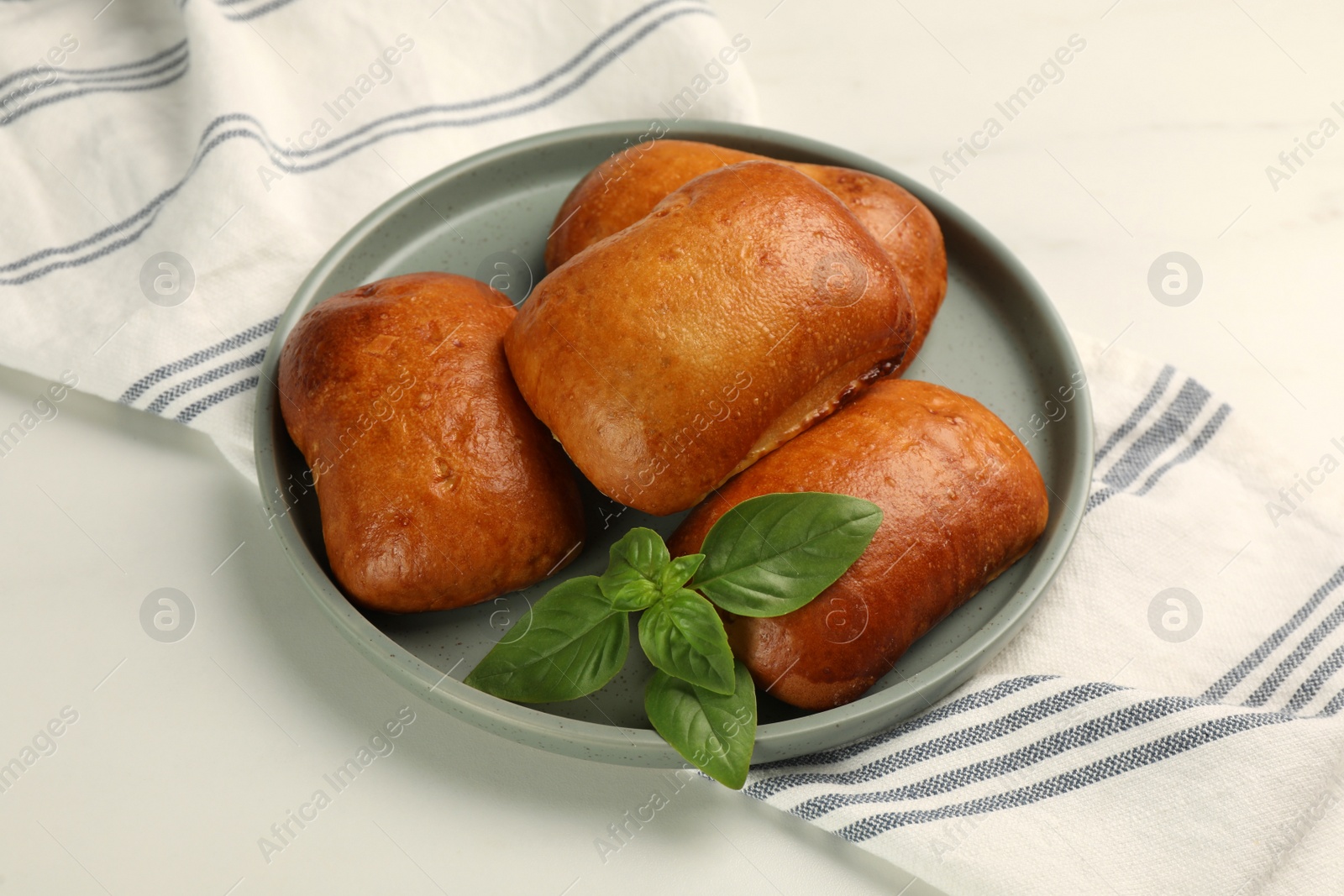 Photo of Delicious baked patties and basil on white table