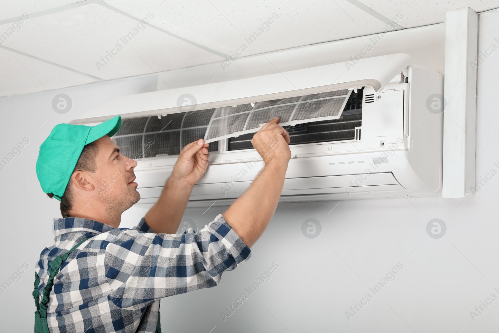 Photo of Male technician cleaning air conditioner indoors