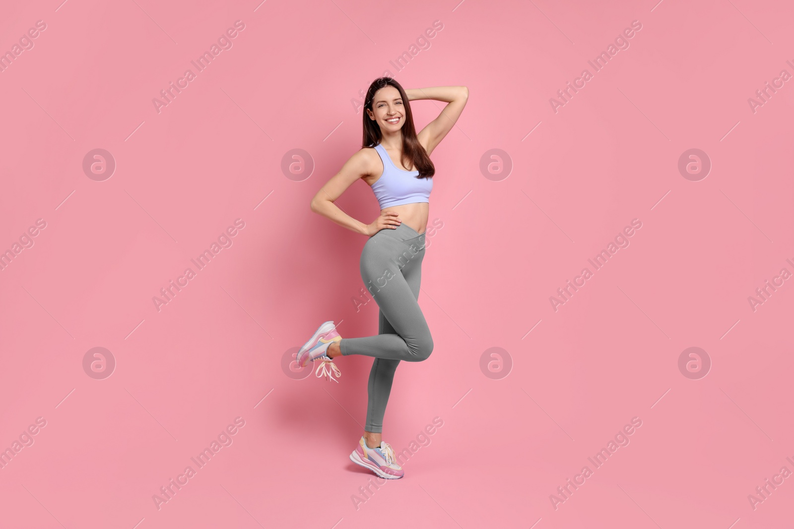 Photo of Happy young woman with slim body posing on pink background