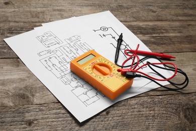 Photo of Wiring diagrams and digital multimeter on wooden table