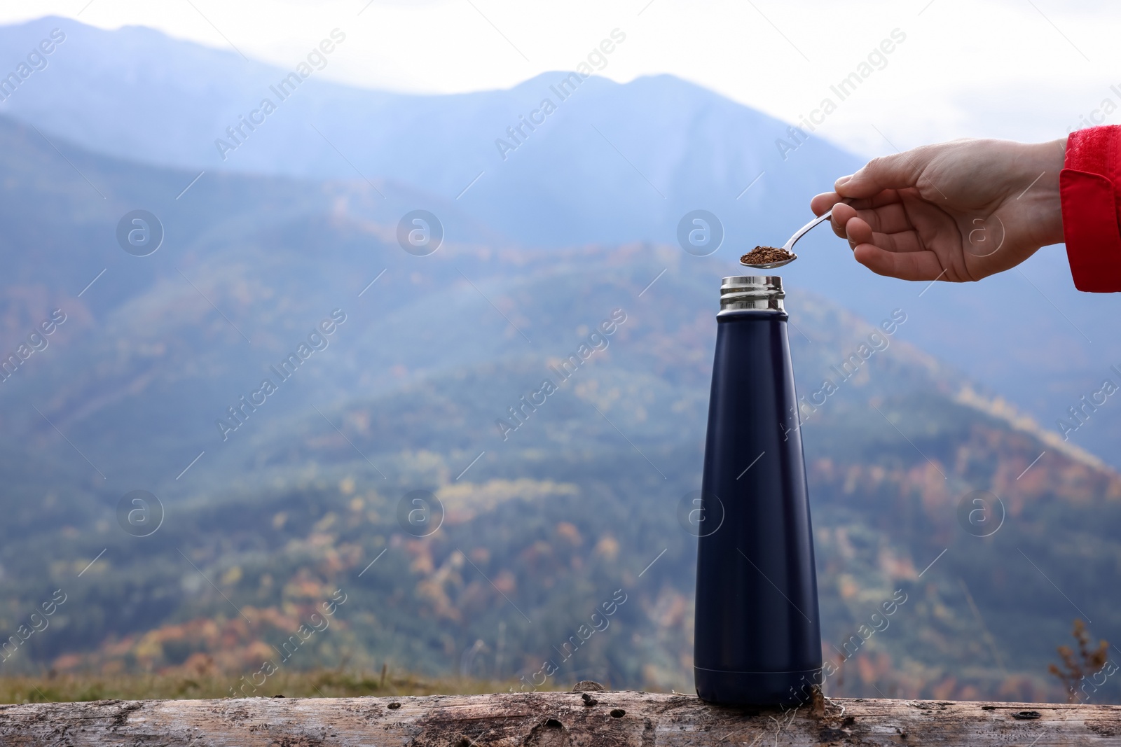 Photo of Woman pouring instant coffee into thermo bottle in mountains, closeup. Space for text