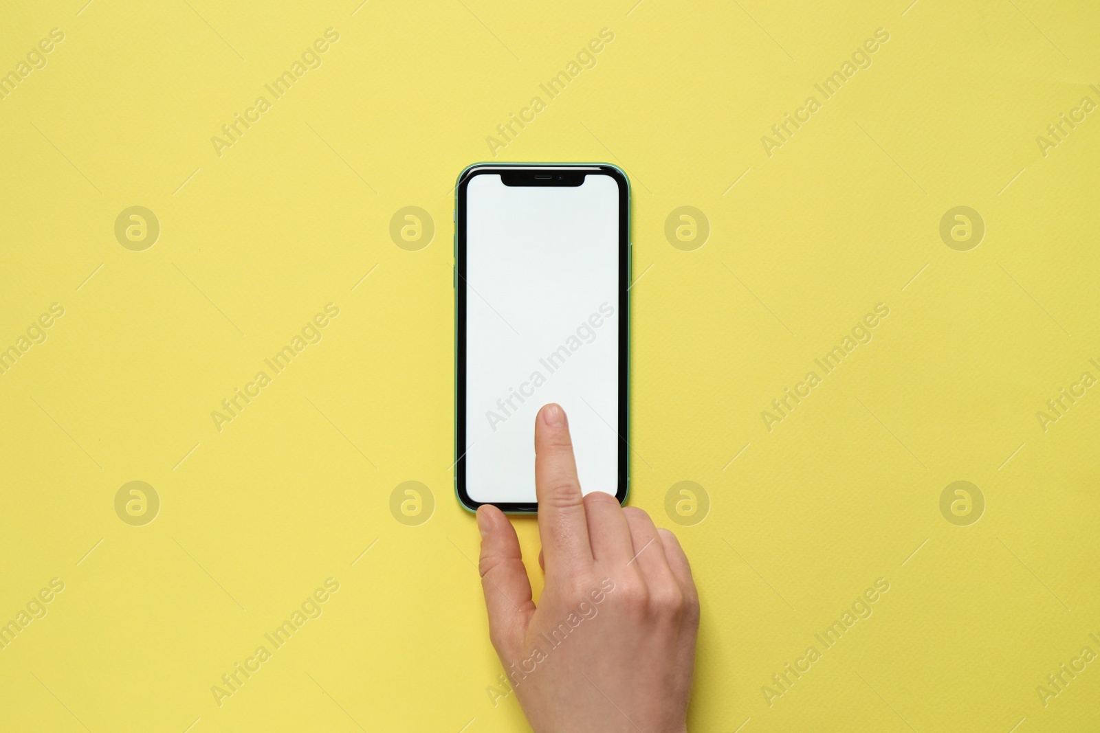 Photo of MYKOLAIV, UKRAINE - JULY 07, 2020: Woman using iPhone 11 on yellow background, top view. Mockup for design