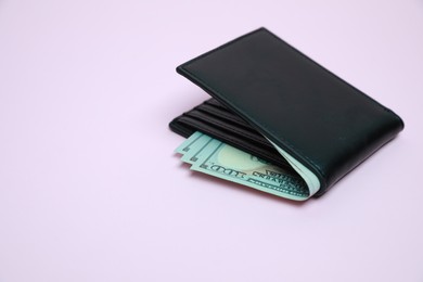 Photo of Stylish black leather wallet with dollar banknotes on light background. Space for text