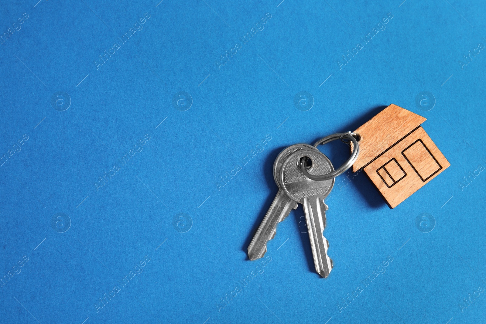 Photo of House keys with trinket on color background, top view. Space for text