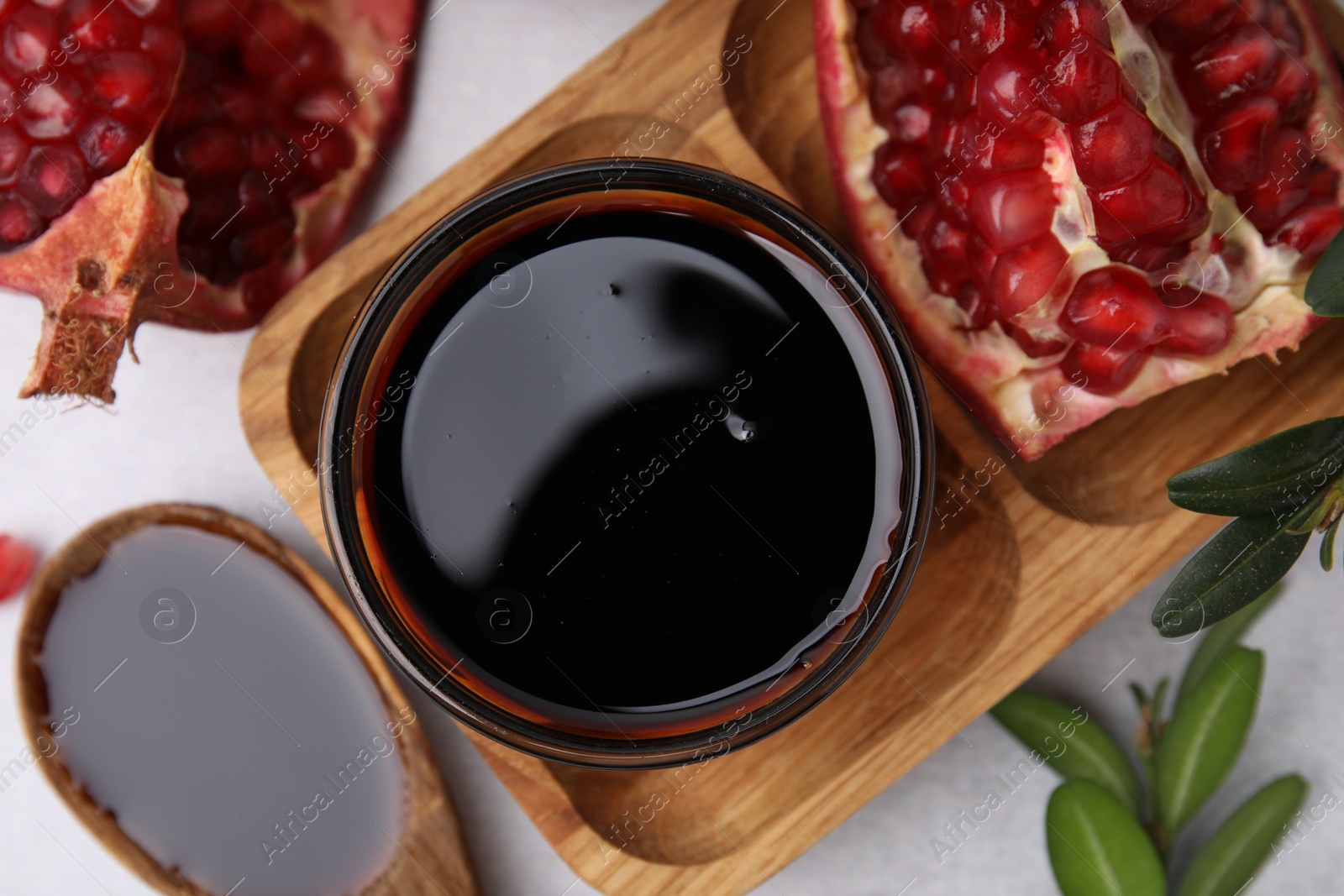 Photo of Tasty pomegranate sauce, fruits and branches on white table, flat lay