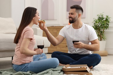 Photo of Affectionate young couple eating pizza and drinking wine at home