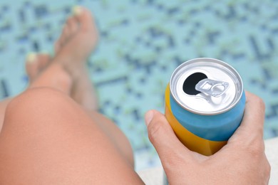 Photo of Woman holding aluminum can with beverage near swimming pool, closeup