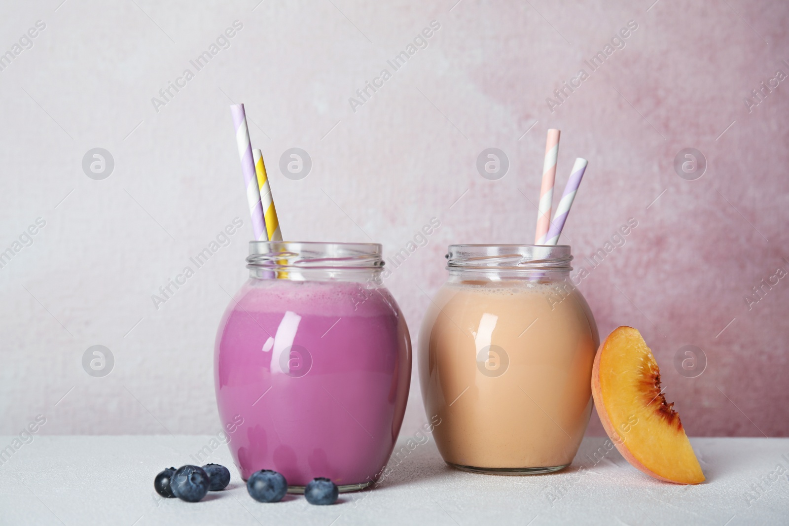 Photo of Jars of tasty milk shakes and fresh fruits on table