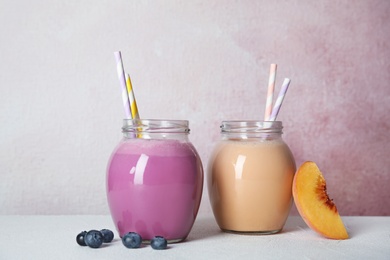 Photo of Jars of tasty milk shakes and fresh fruits on table