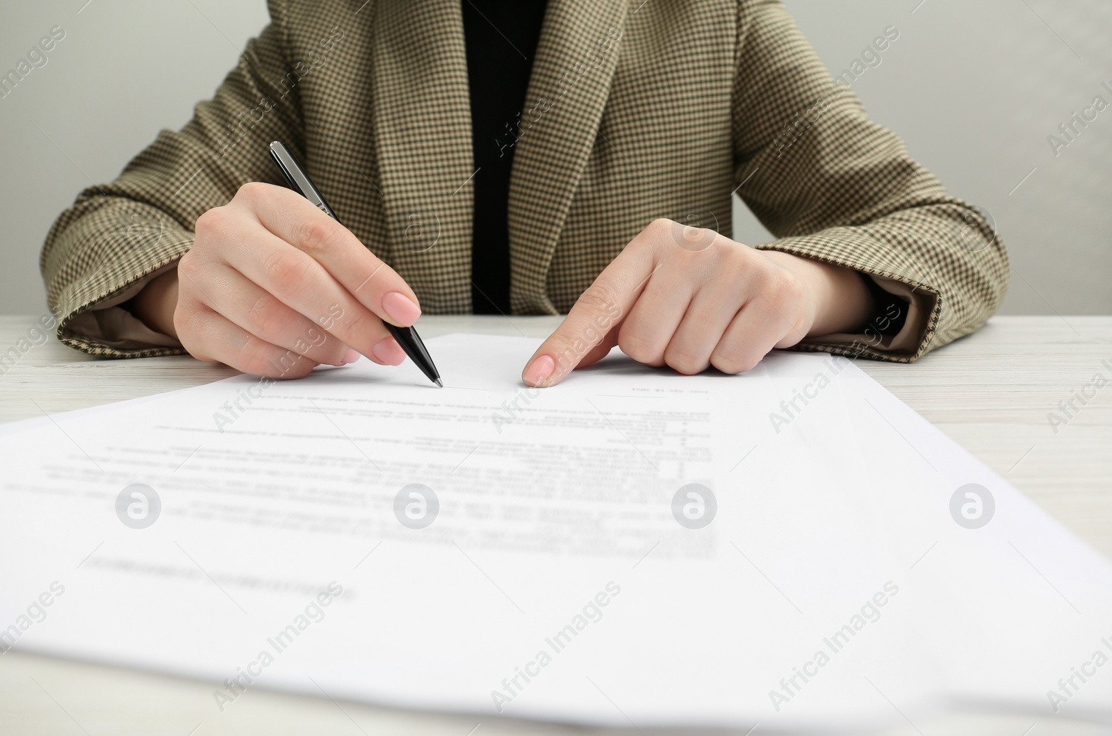 Photo of Woman signing document at wooden table, closeup