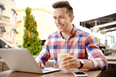 Young man working with laptop at desk in cafe