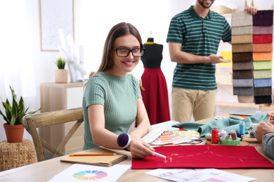 Fashion designer with colleagues creating new clothes in studio