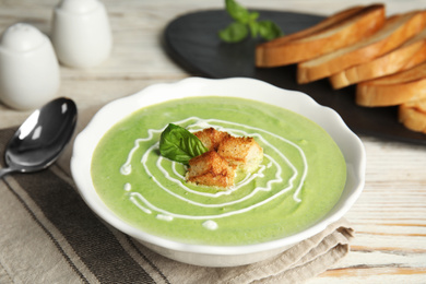 Delicious broccoli cream soup with croutons served on white wooden table