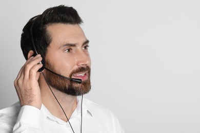 Hotline operator with headset on light grey background, space for text