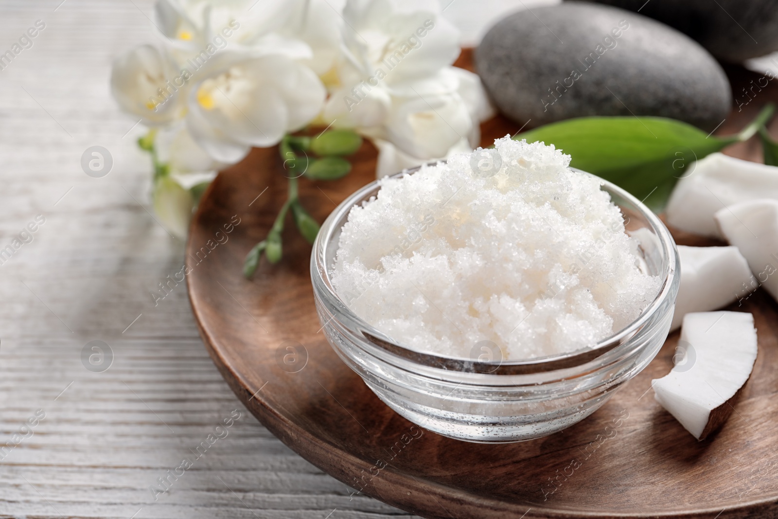 Photo of Glass bowl with natural coconut scrub on wooden tray