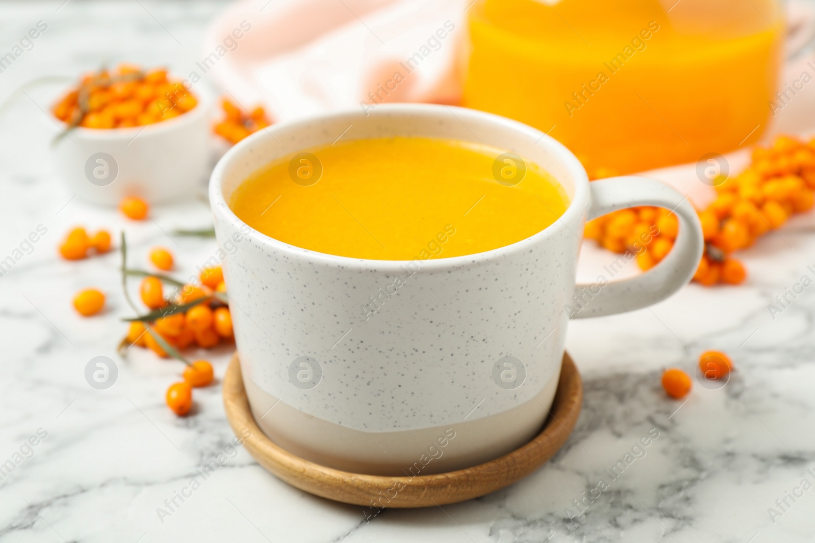 Photo of Delicious sea buckthorn tea and fresh berries on white marble table