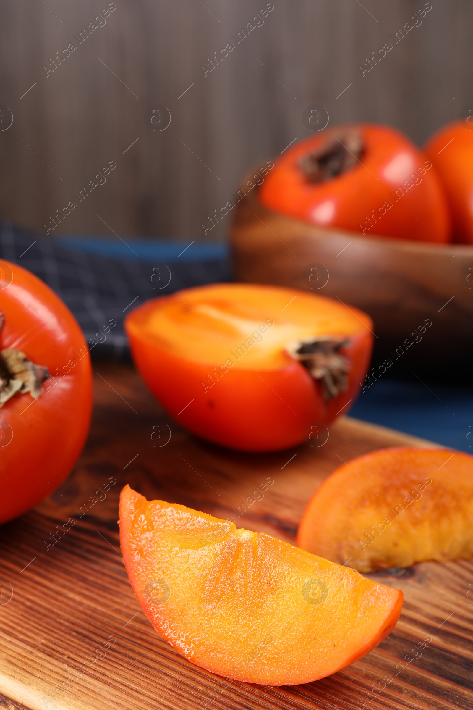 Photo of Delicious cut persimmon on wooden board, closeup