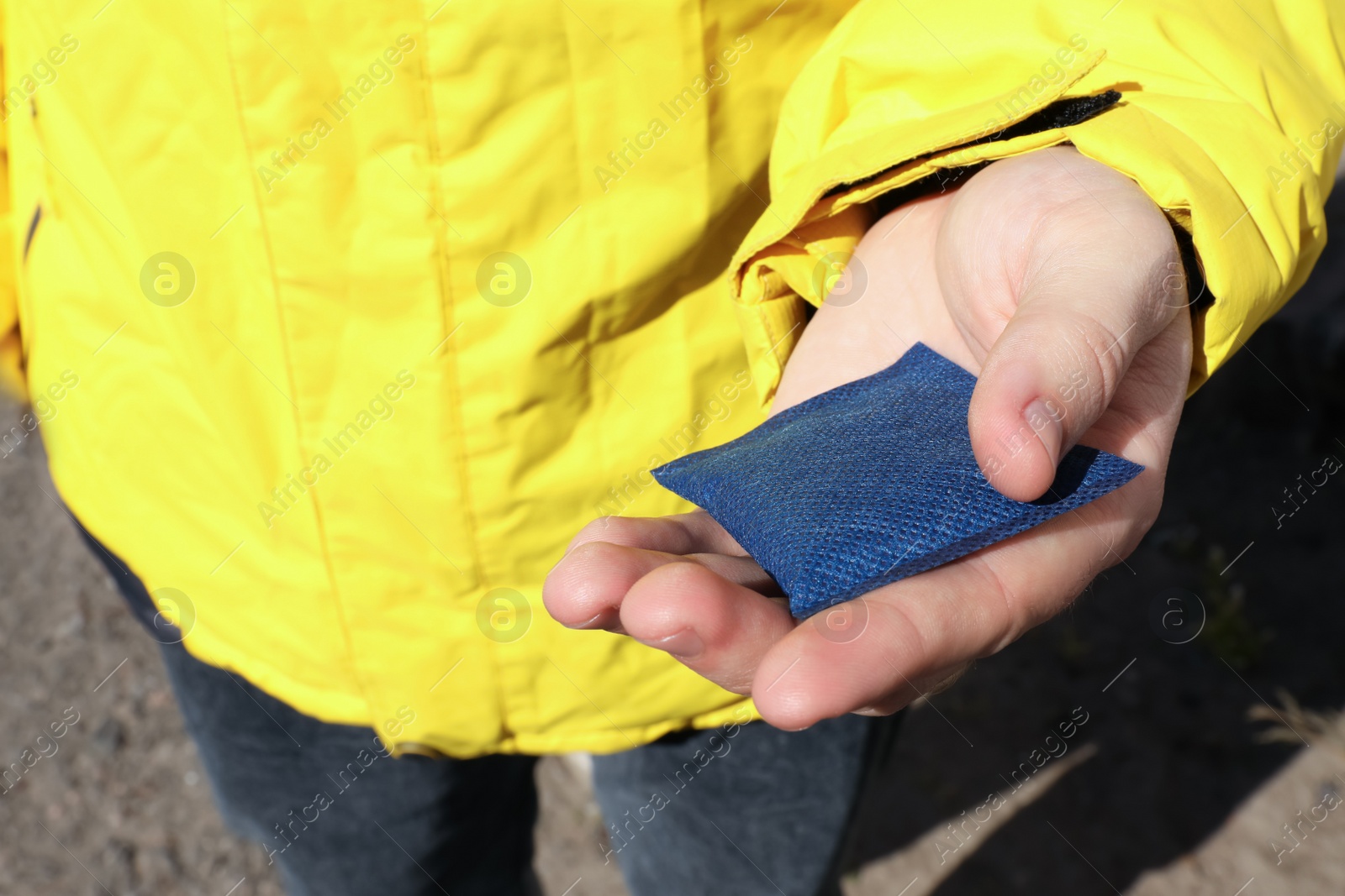 Photo of Man holding hand warmer outdoors, closeup view