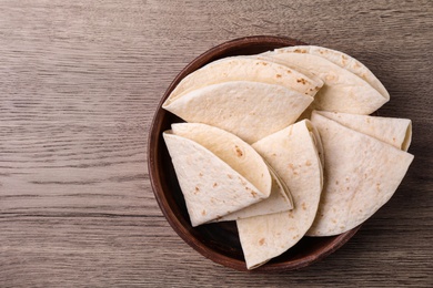 Photo of Bowl with corn tortillas and space for text on wooden background, top view. Unleavened bread