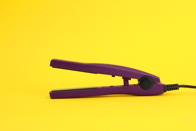 Photo of Modern hair iron for straightening on color background