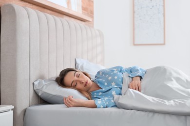 Photo of Young woman sleeping in comfortable bed with silky linens