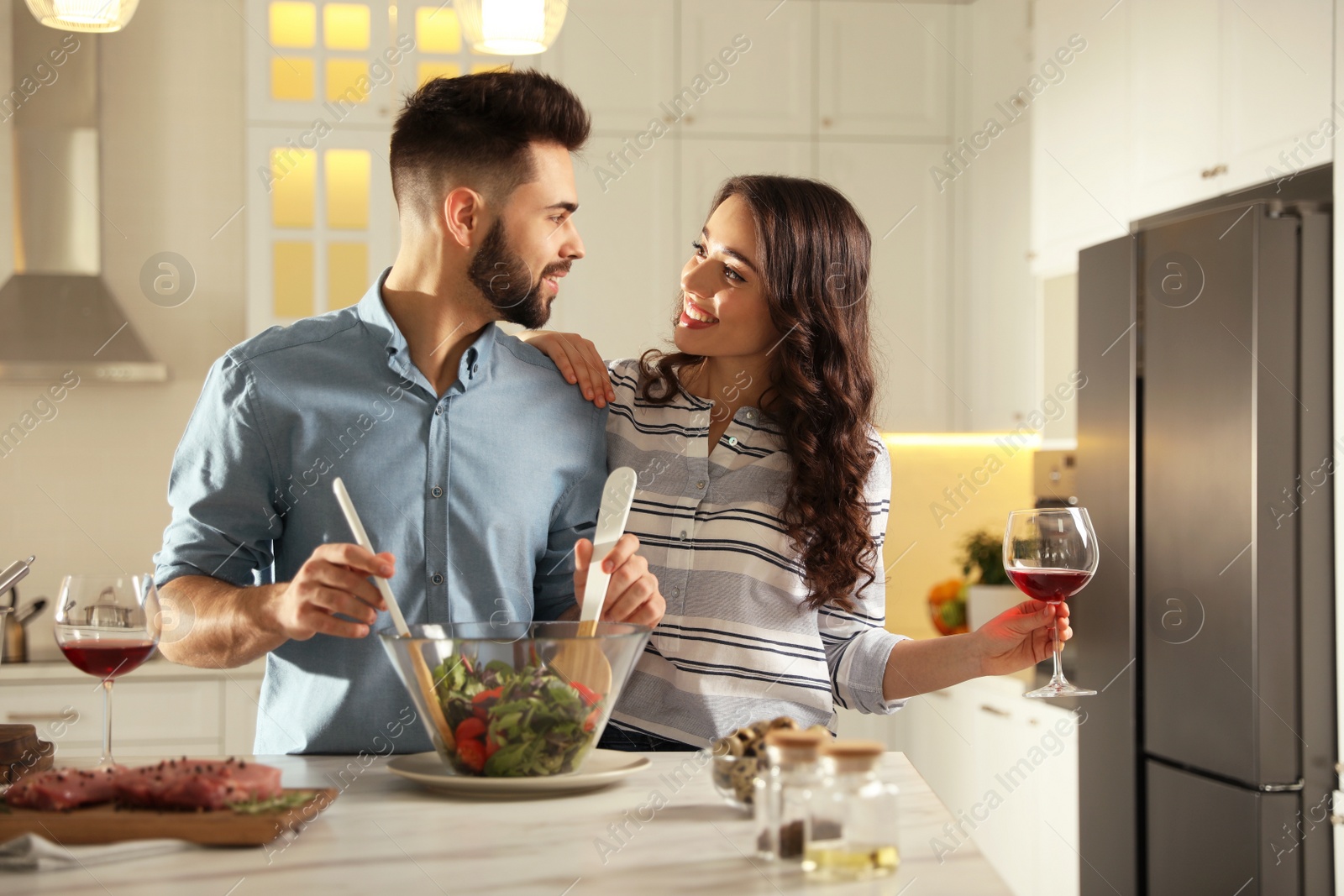 Photo of Lovely young couple cooking salad together in kitchen