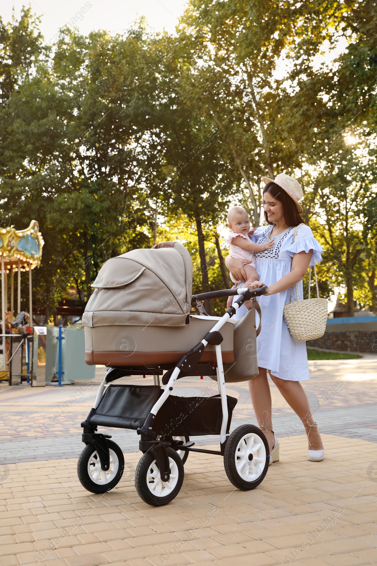 Photo of Happy mother with baby and stroller walking in park