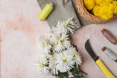 Photo of Flat lay composition with knife, threads and Chrysanthemum flowers on light textured table, space for text