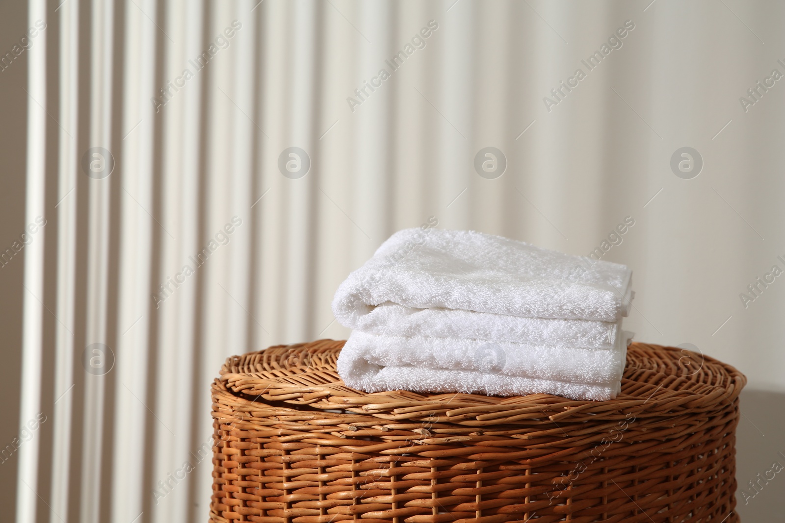 Photo of Soft towels on wicker basket indoors, space for text