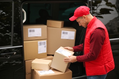 Photo of Courier with parcels near delivery van outdoors