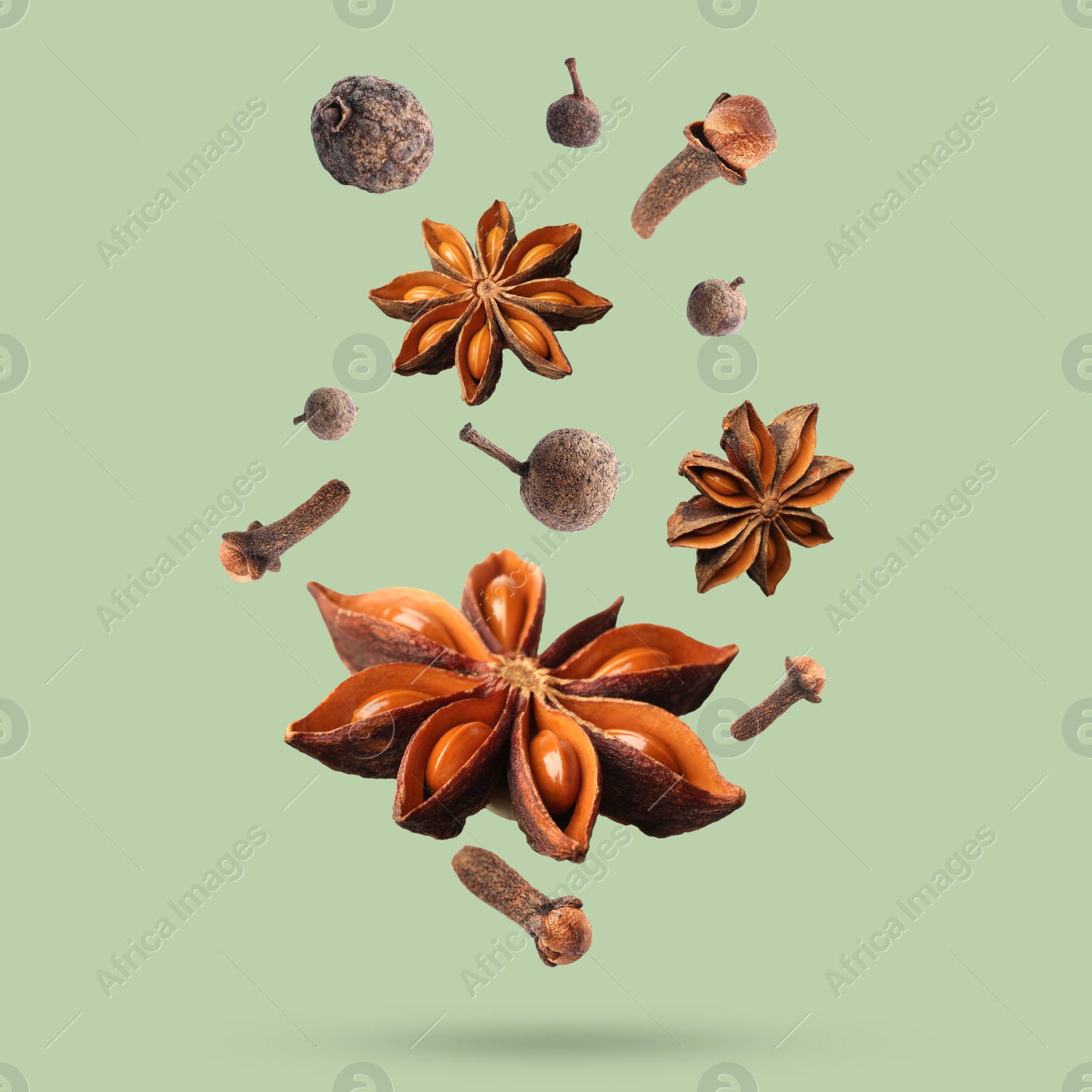 Image of Different spices falling on light green background