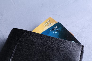 Credit cards in leather wallet on grey textured table, closeup