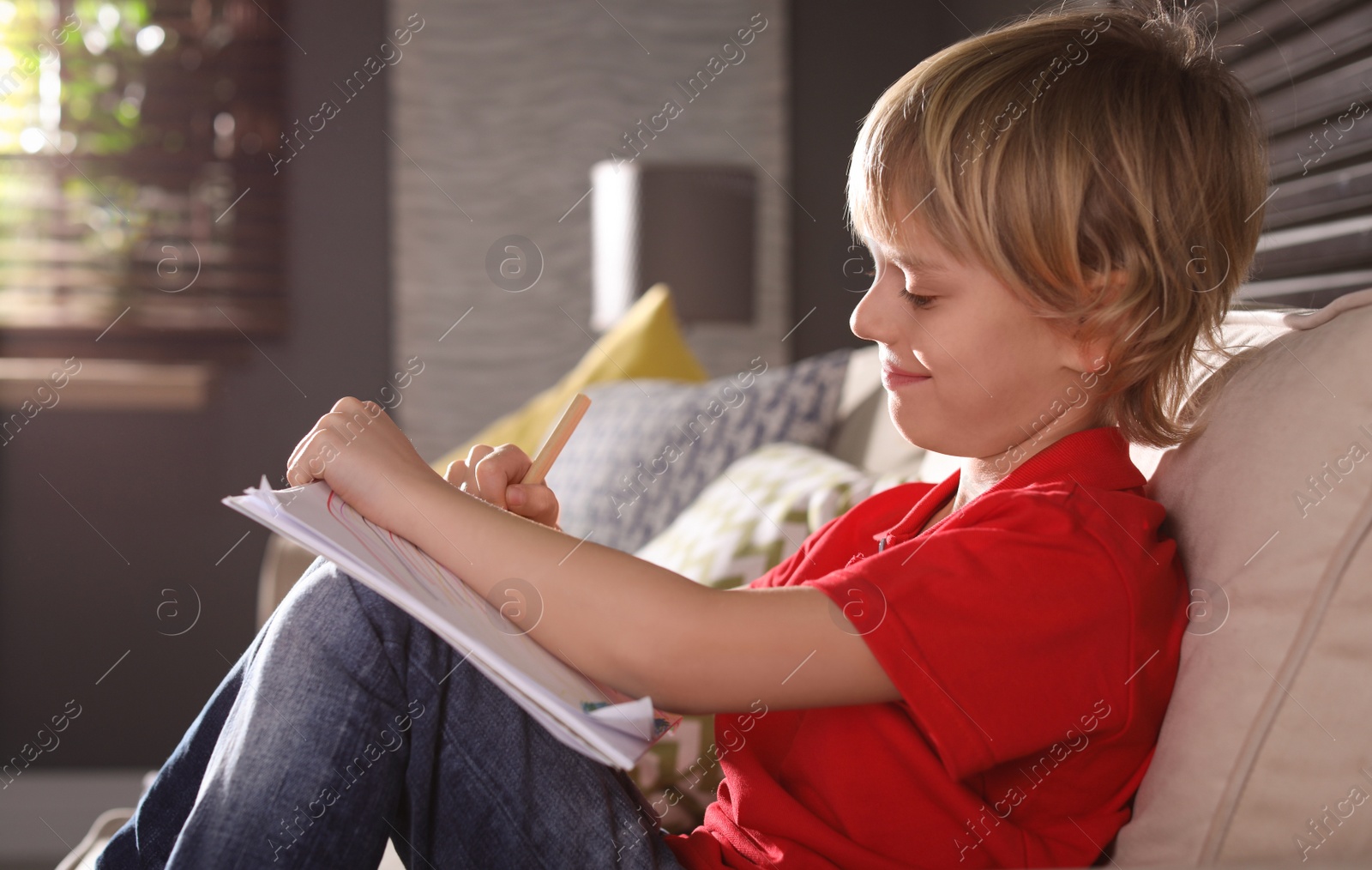 Photo of Little boy drawing on sofa at home. Creative hobby