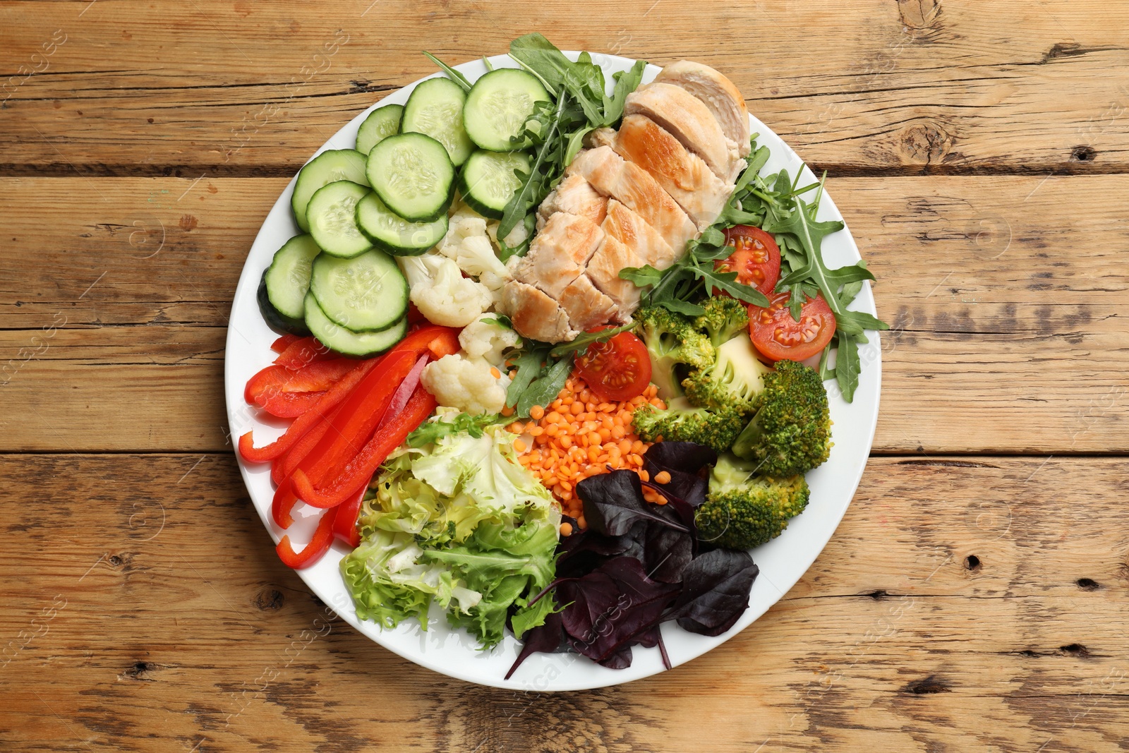 Photo of Balanced diet and healthy foods. Plate with different delicious products on wooden table, top view