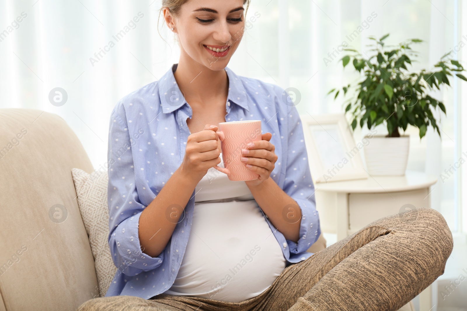 Photo of Happy pregnant woman drinking tea at home