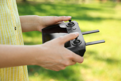 Photo of Woman holding new modern drone controller outdoors, closeup of hands