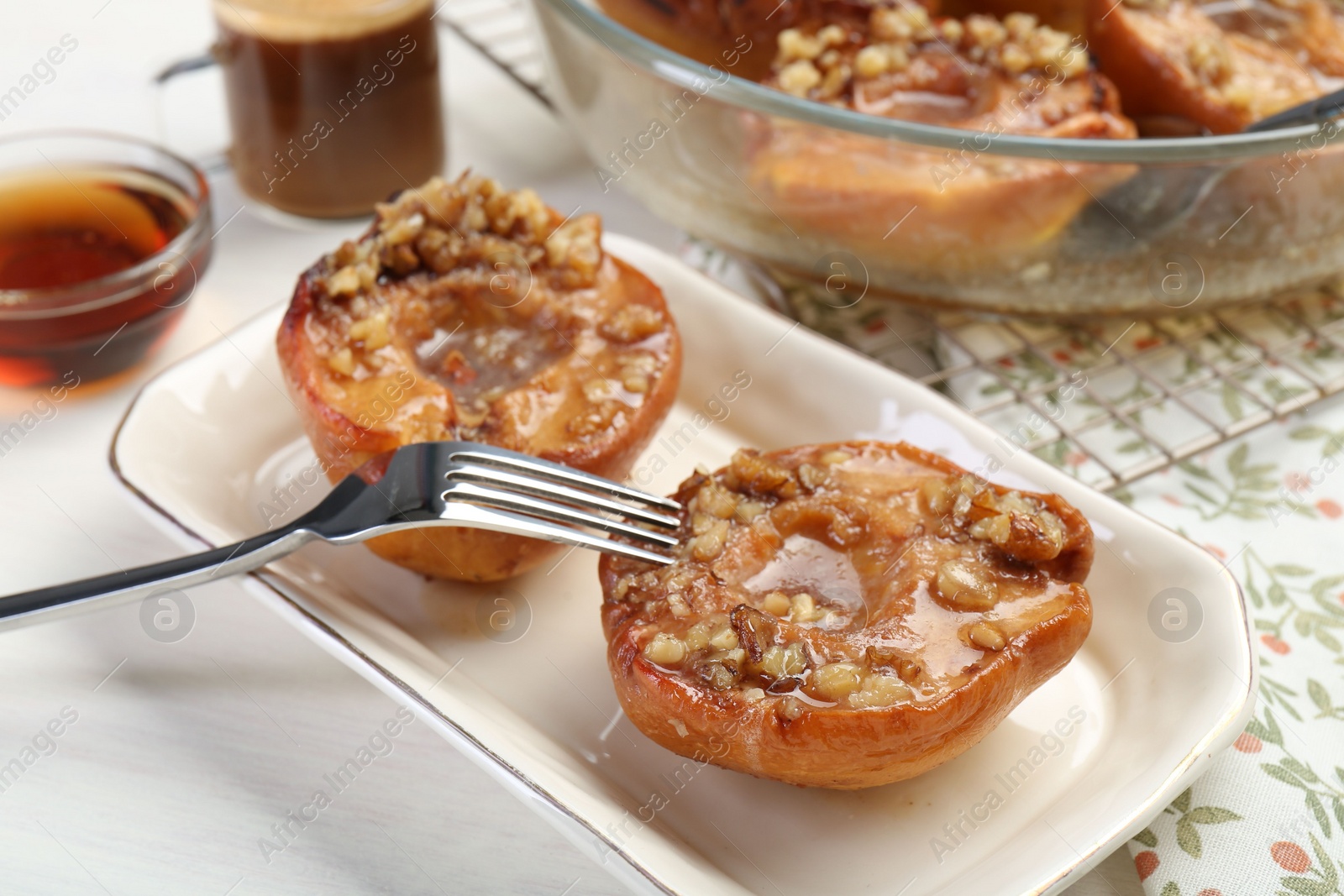 Photo of Delicious quinces baked with honey and walnuts on white table