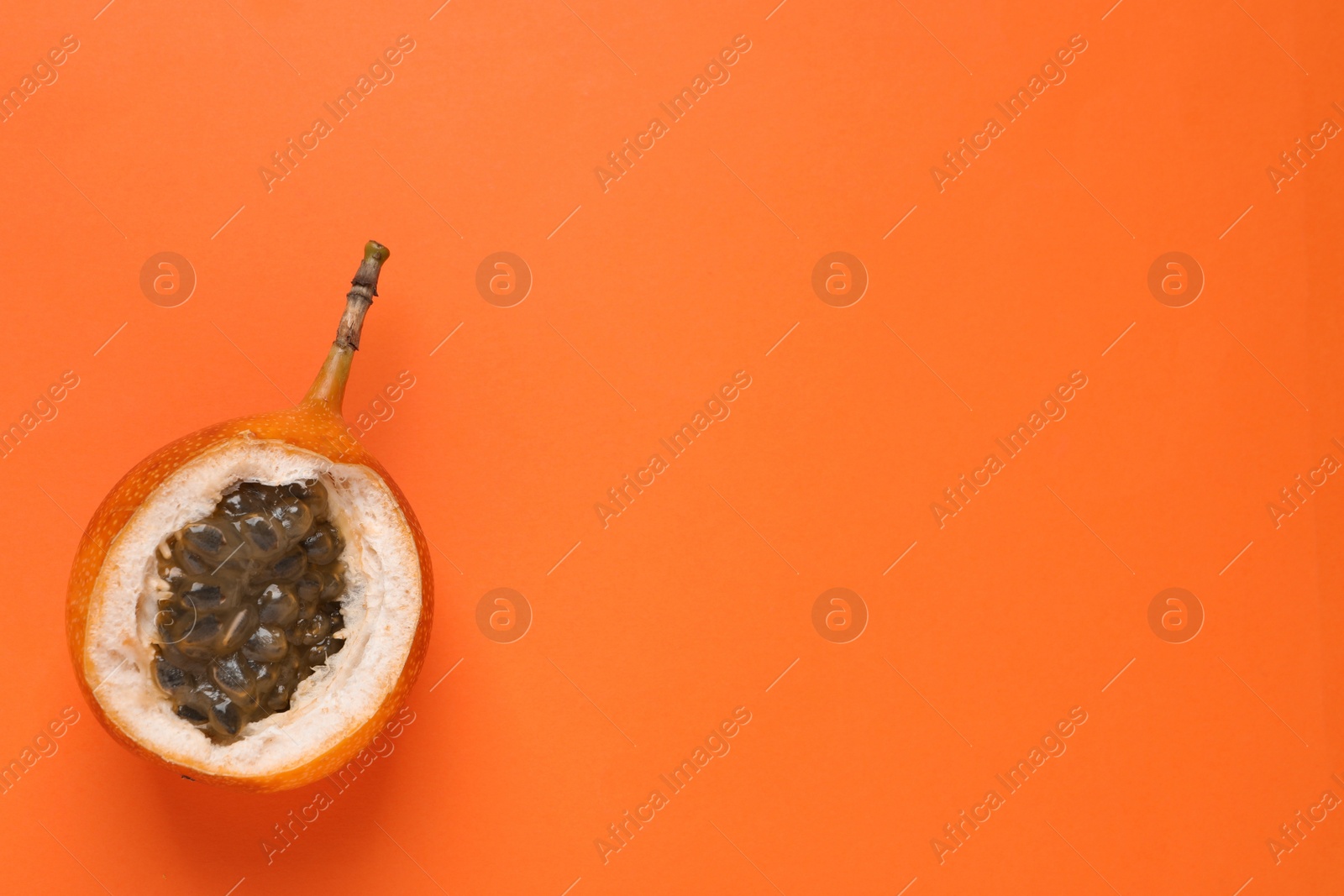 Photo of Delicious ripe granadilla on orange background, top view. Space for text