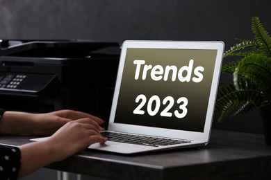 Trends 2023 text on laptop display. Woman using device, closeup