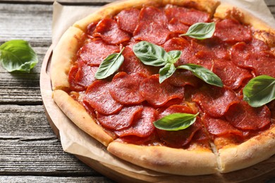 Photo of Tasty pepperoni pizza with basil on wooden table, closeup