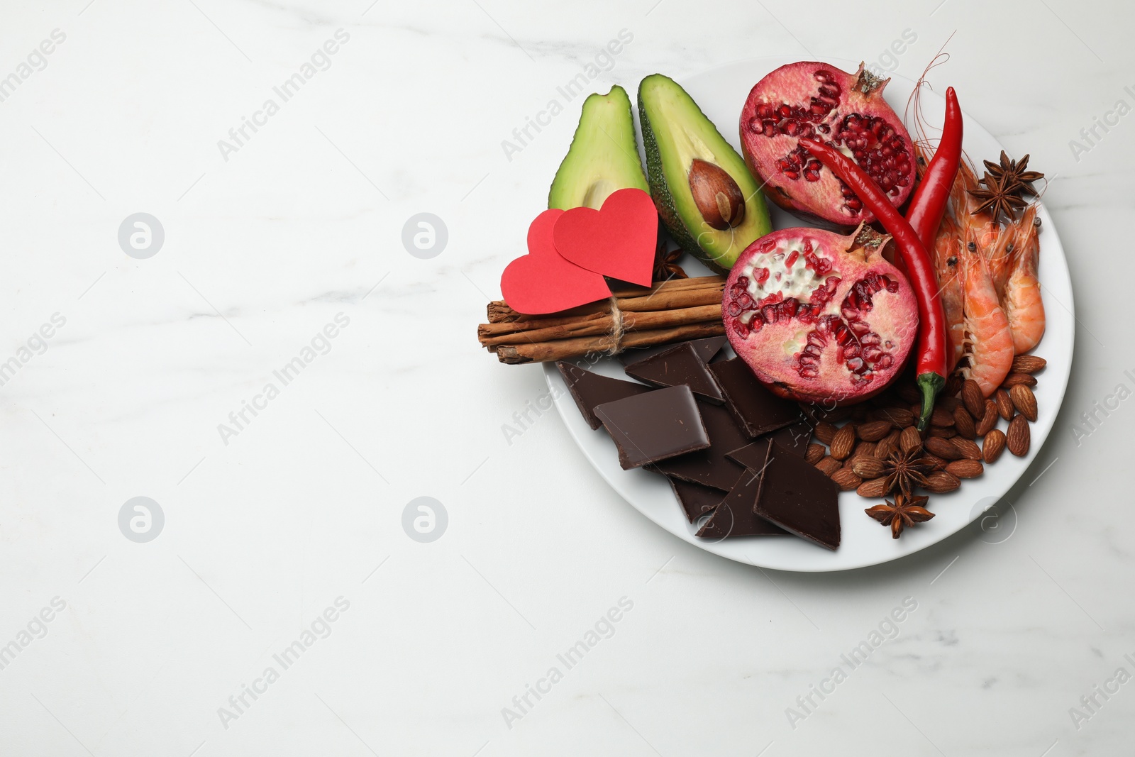 Photo of Natural aphrodisiac. Different products and paper hearts on white marble table, top view. Space for text