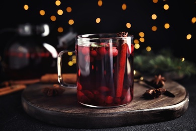 Photo of Tasty hot cranberry tea with cinnamon on black table, closeup