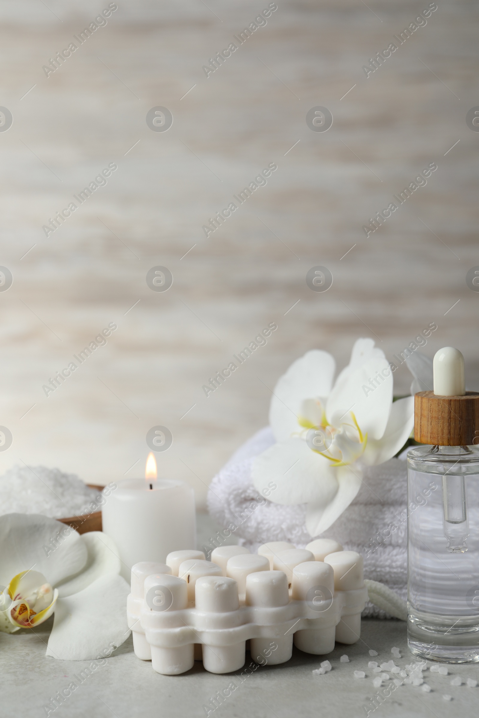 Photo of Beautiful composition with different spa products, burning candles and flowers on light grey table. Space for text