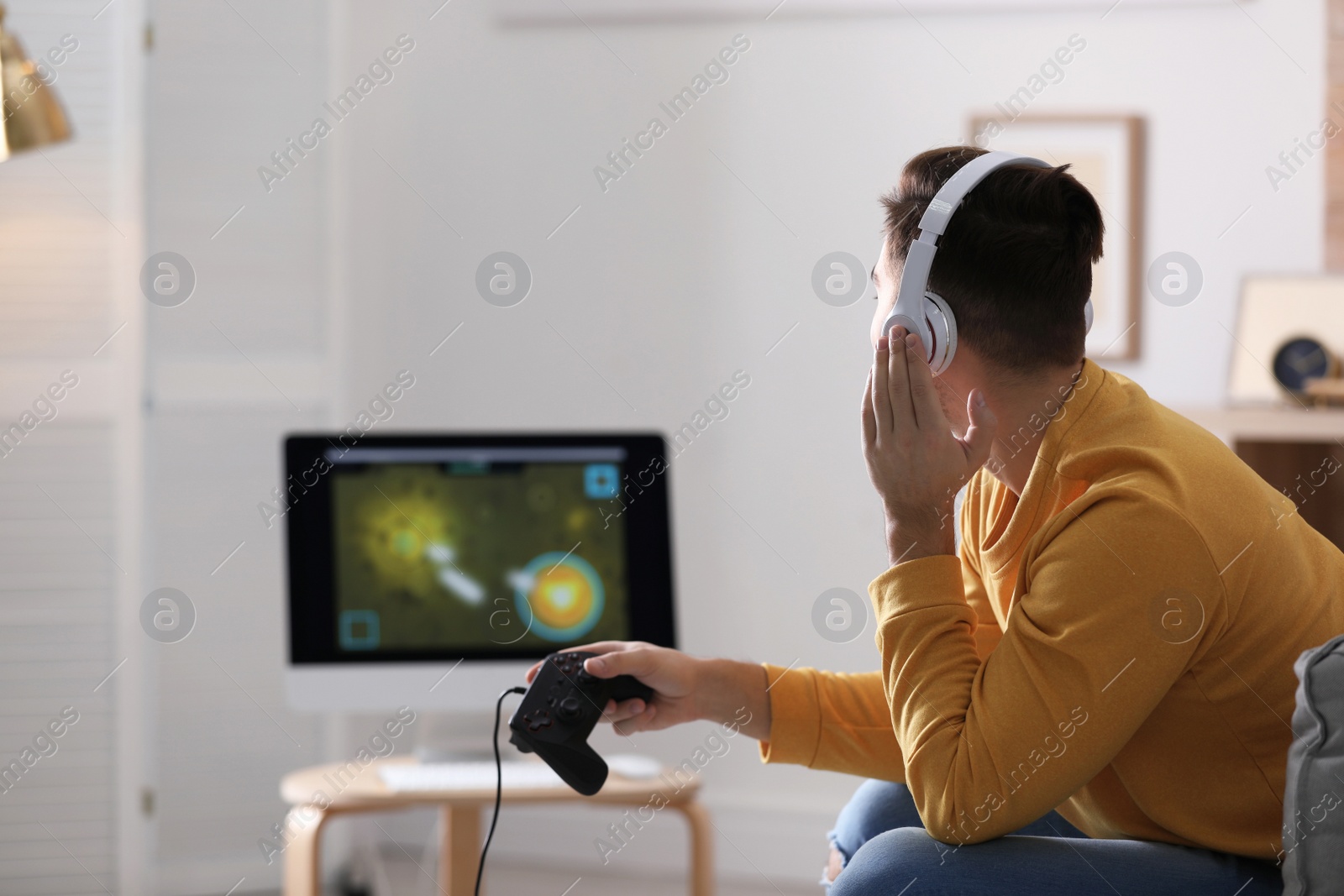 Photo of Young man playing video games at home